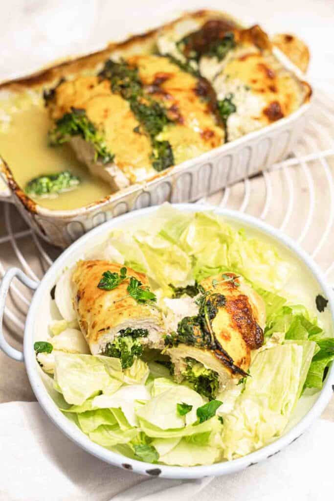 Chicken roll-ups with greens and cheese, served on a white dish.