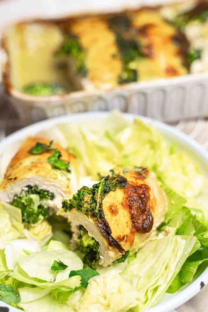 Chicken roll-ups with greens and cheese, served on a white dish.