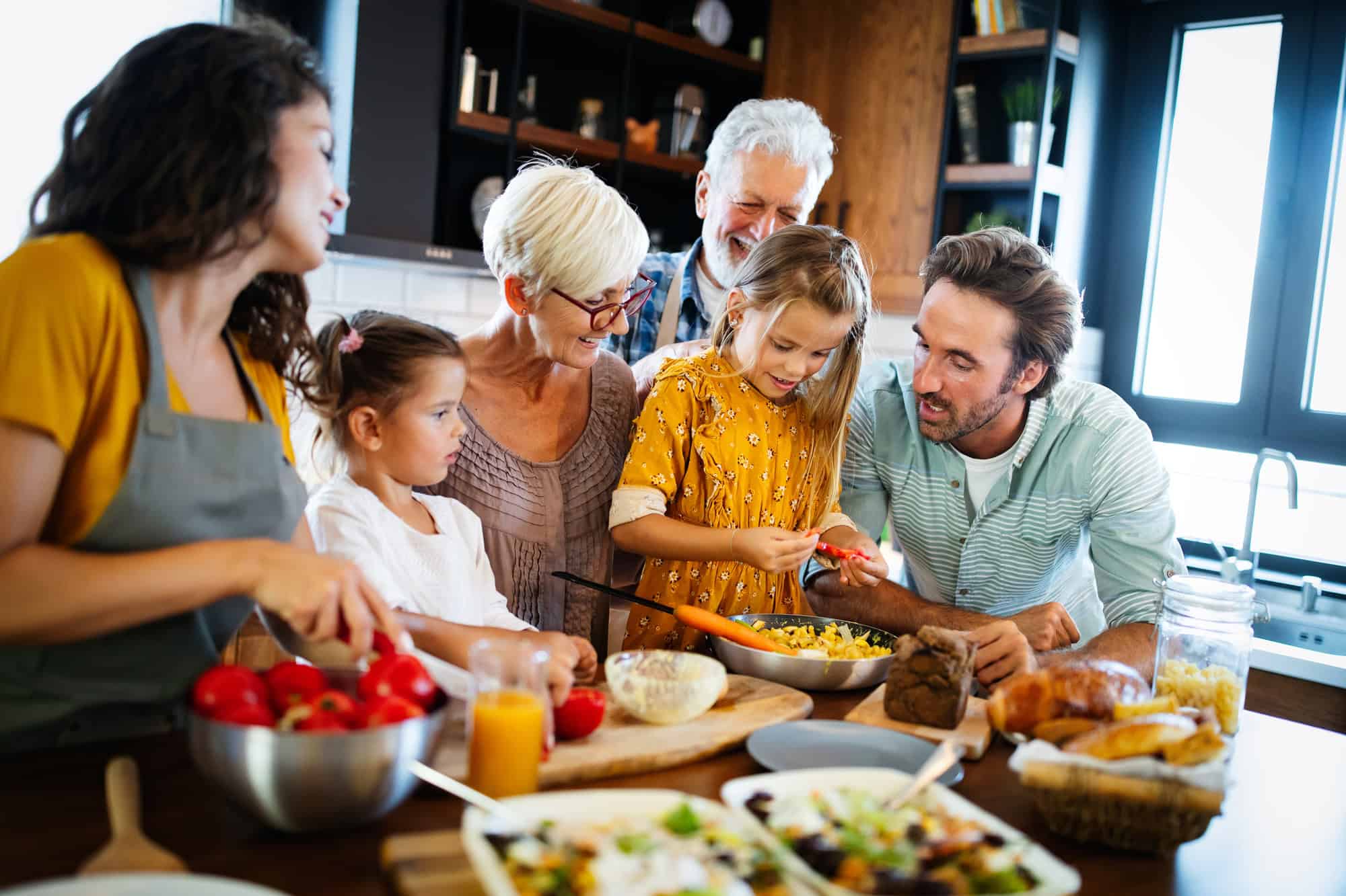 Grandparents, parents and children spending happy time in the kitchen.