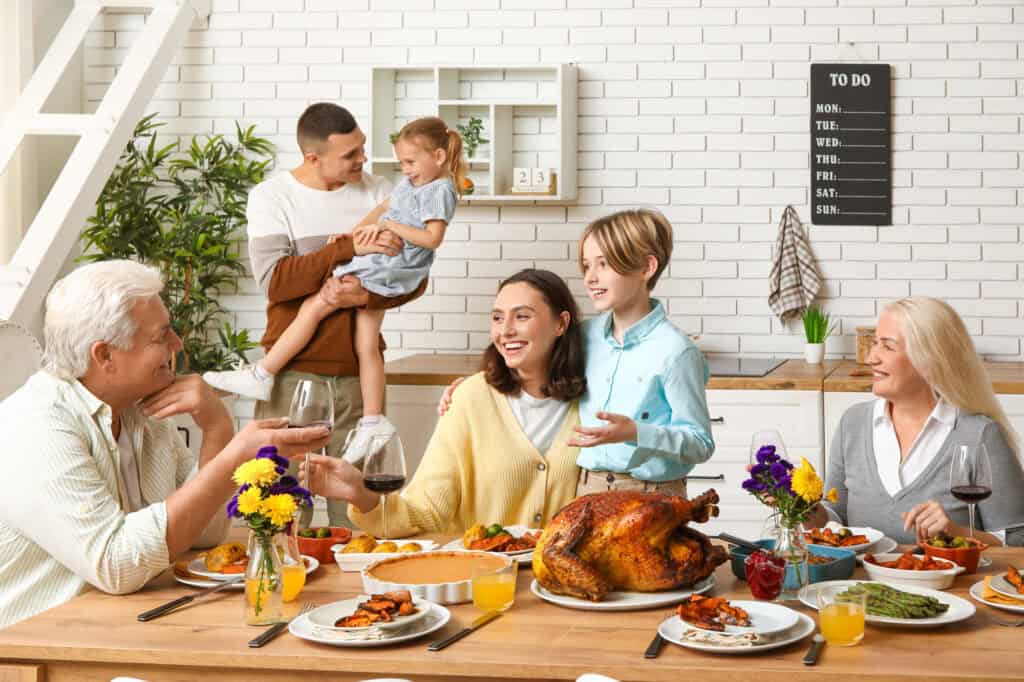 Happy family having dinner at festive table on Thanksgiving Day.