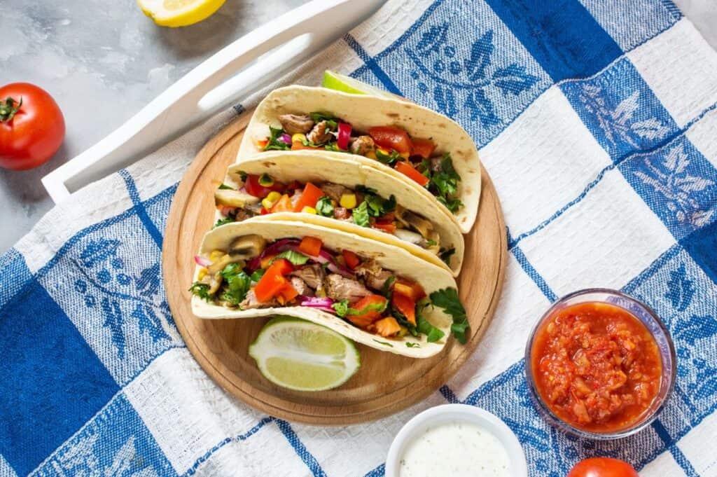 Mexican pork tacos with vegetables. Tacos al pastor on wooden blue rustic background.