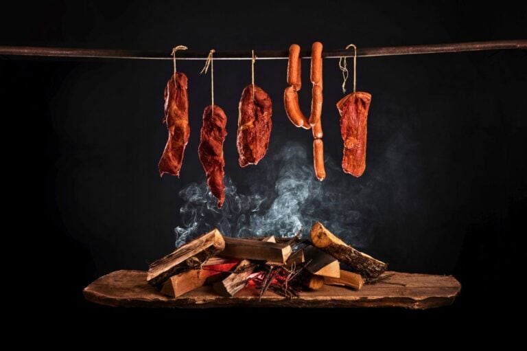 Smoked ham, bacon, pork neck and sausages in a smokehouse.