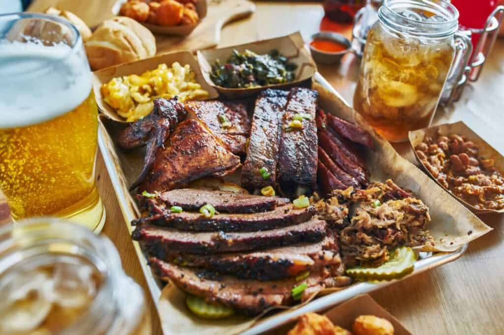 Texas style bbq tray with smoked brisket, st louis ribs, pulled pork, chicken, hot links, and sides.