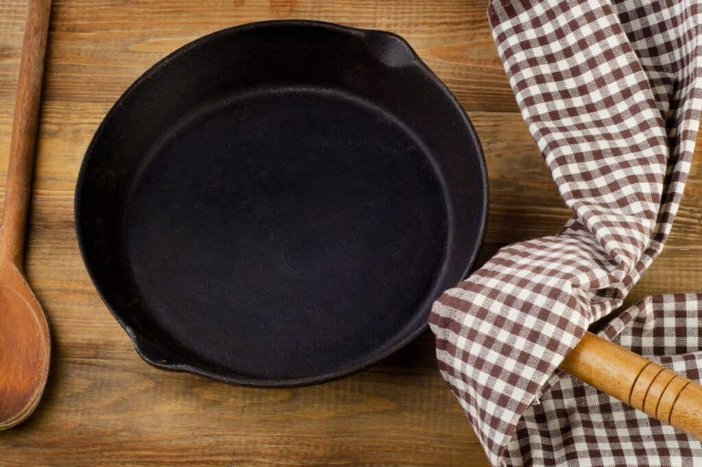 Vintage cast iron skillet on rustic wood background.