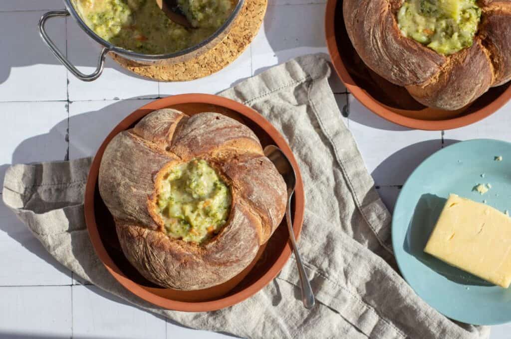 Bowl of broccoli cheddar soup in a crusty sourdough bread bowl.