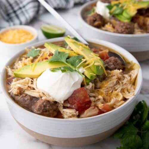 A hearty bowl of taco soup garnished with sour cream and shredded cheese.