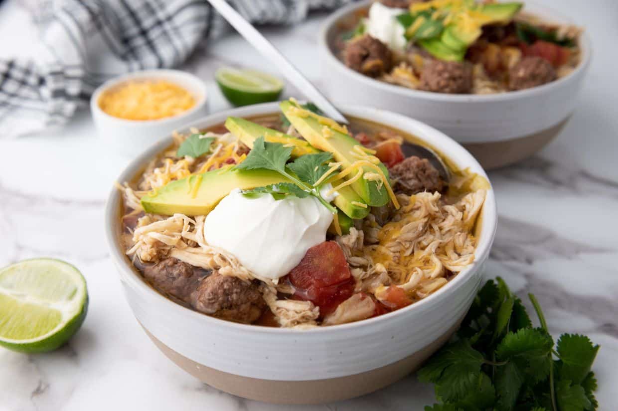 A hearty bowl of taco soup garnished with sour cream and shredded cheese.