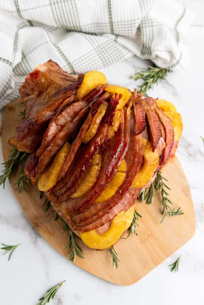 A cooked ham with golden brown sugar glaze and pineapple slices.