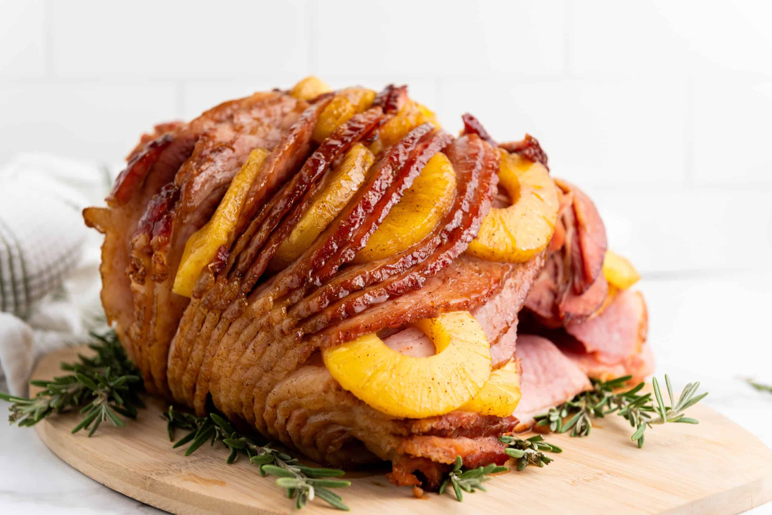 A ham covered in a shiny brown sugar glaze surrounded by pineapple slices.