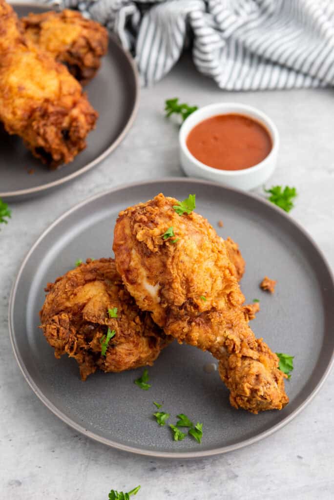 Buttermilk fried chicken served with a side of tangy dipping sauce and a garnish of fresh herbs.