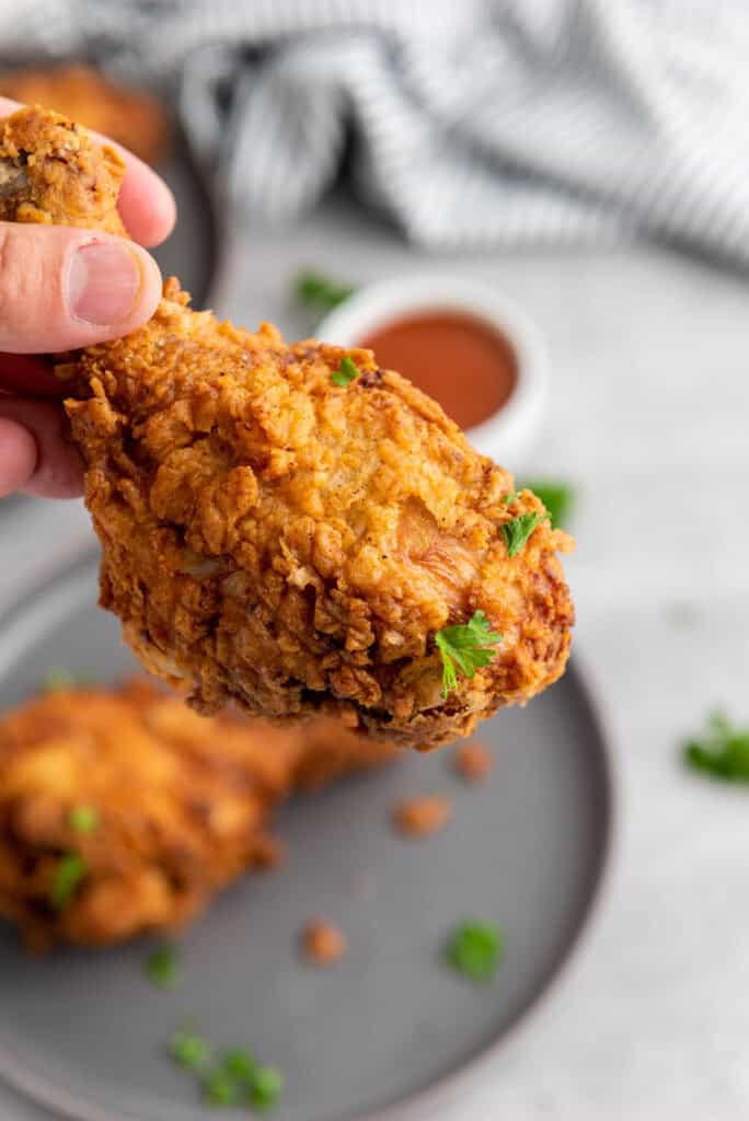 Close-up of a crispy, golden brown buttermilk fried chicken leg with crunchy skin.