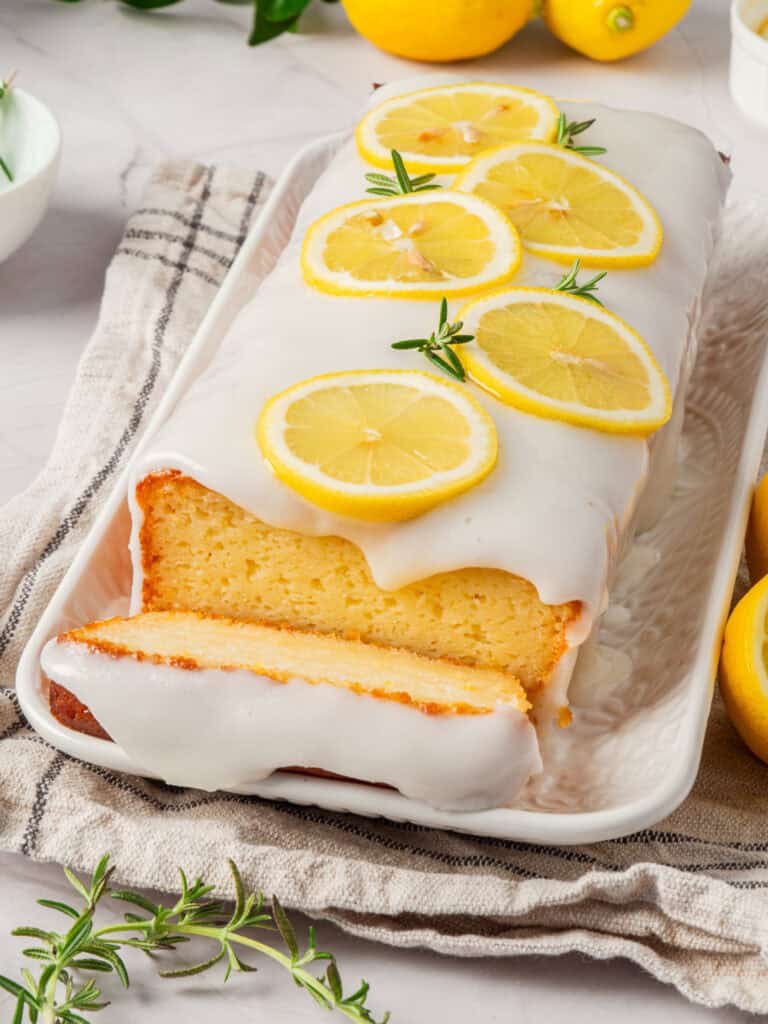 Close-up of a slice of lemon loaf cake with a lemon slices highlighting its moist texture.