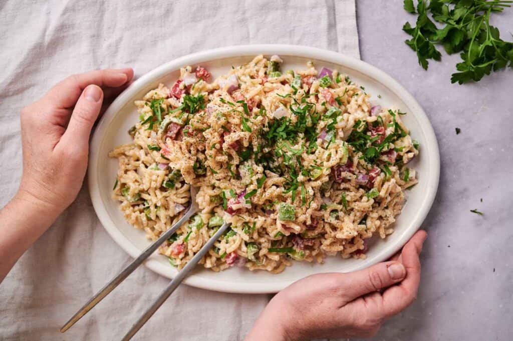 Macaroni salad garnished with parsley in a white serving dish.