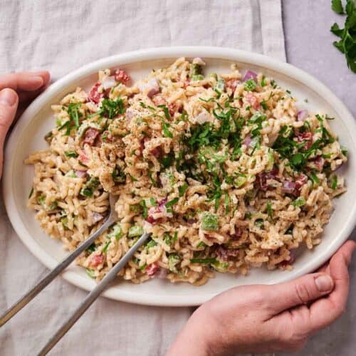 Macaroni salad garnished with parsley in a white serving dish.