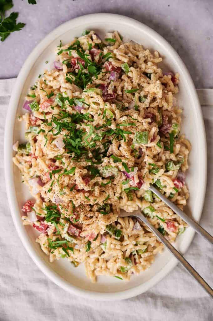 Close-up of macaroni salad with herbs and creamy dressing.