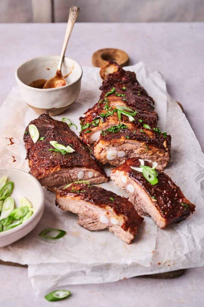 Oven-baked ribs brushed with barbecue sauce on a baking sheet.