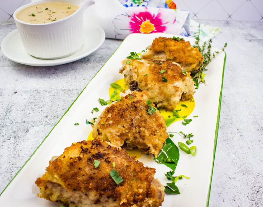 Baked chicken thighs served with a side of creamy onion sauce.