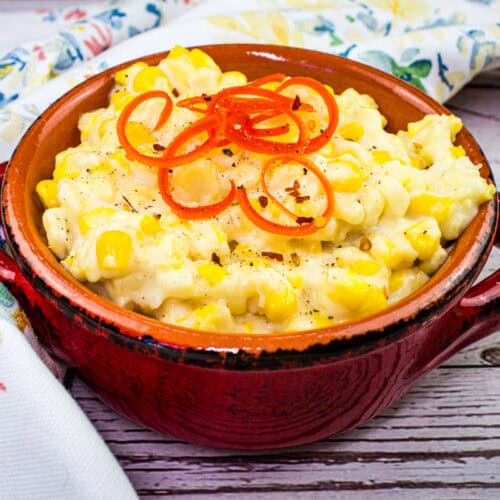 Bowl of creamy, homemade creamed corn with a sprinkle of pepper.