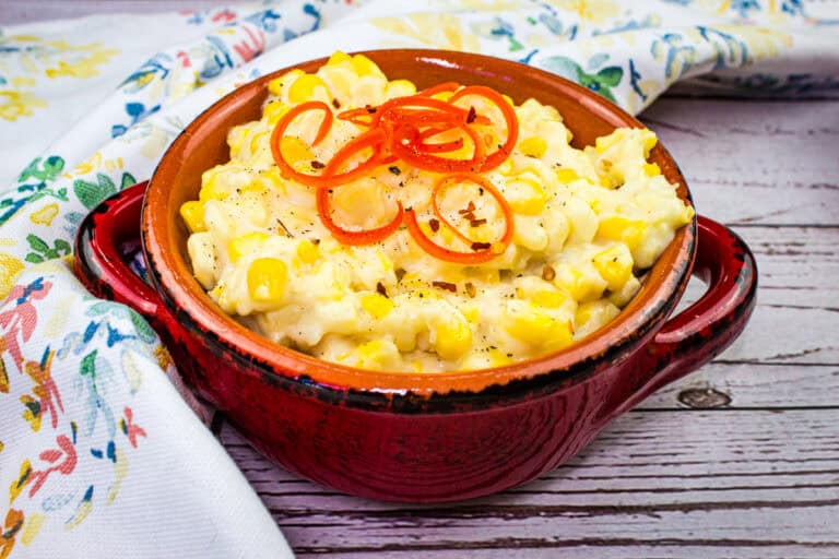 Bowl of creamy, homemade creamed corn with a sprinkle of pepper.