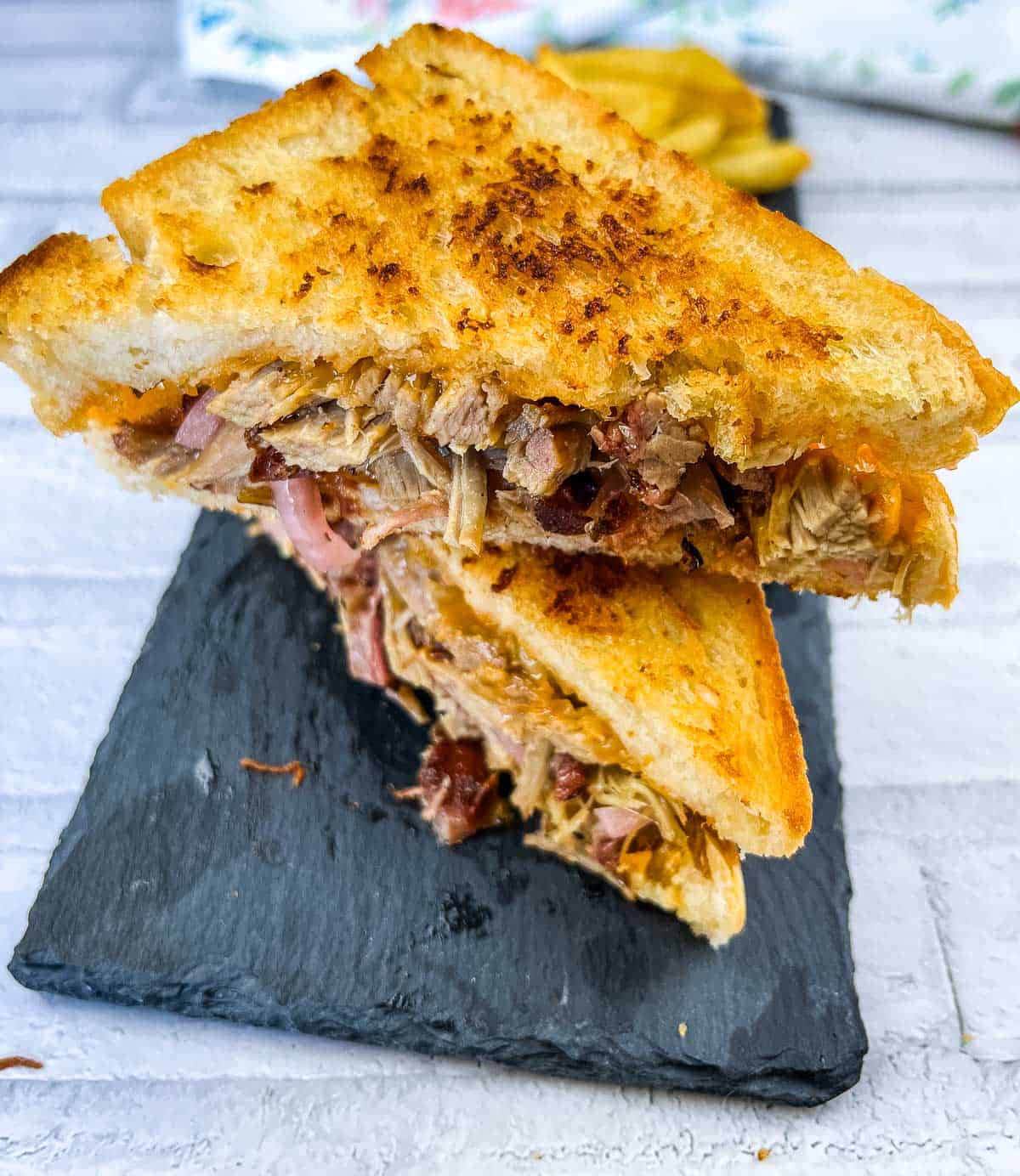 A pulled pork grilled cheese sandwich on a slate plate.