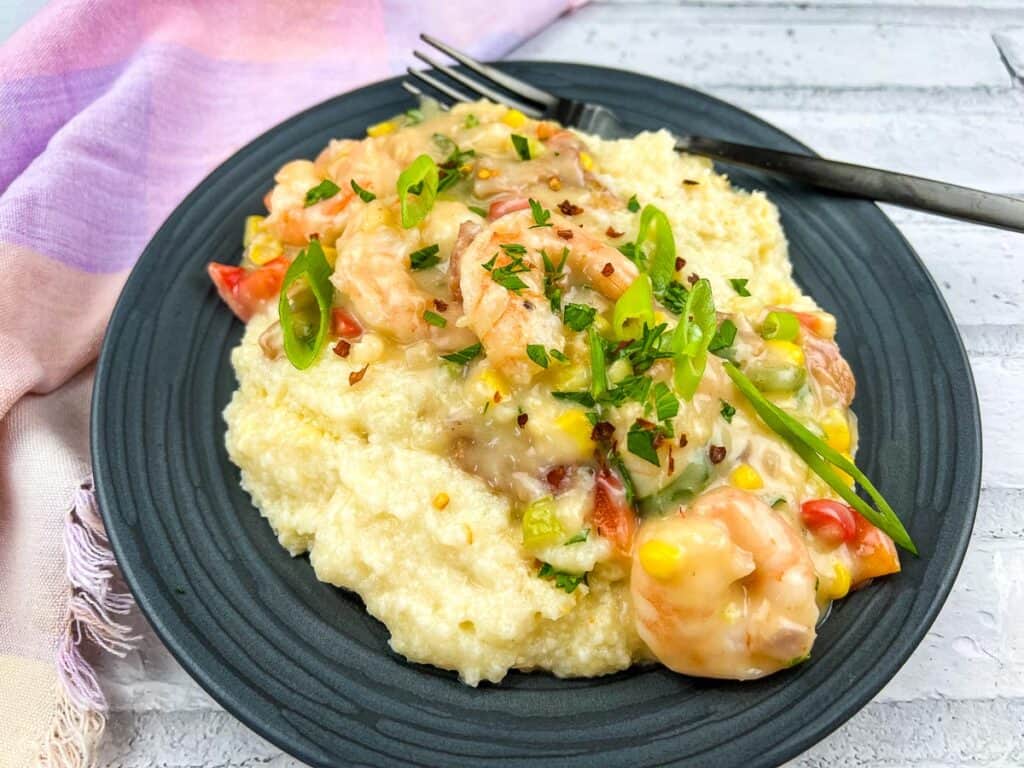 Shrimp and Grits Casserole with colorful veggies and spices, served on a black plate.