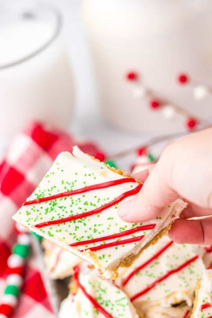 Close-up of Christmas crack topped with red icing and green sprinkles.