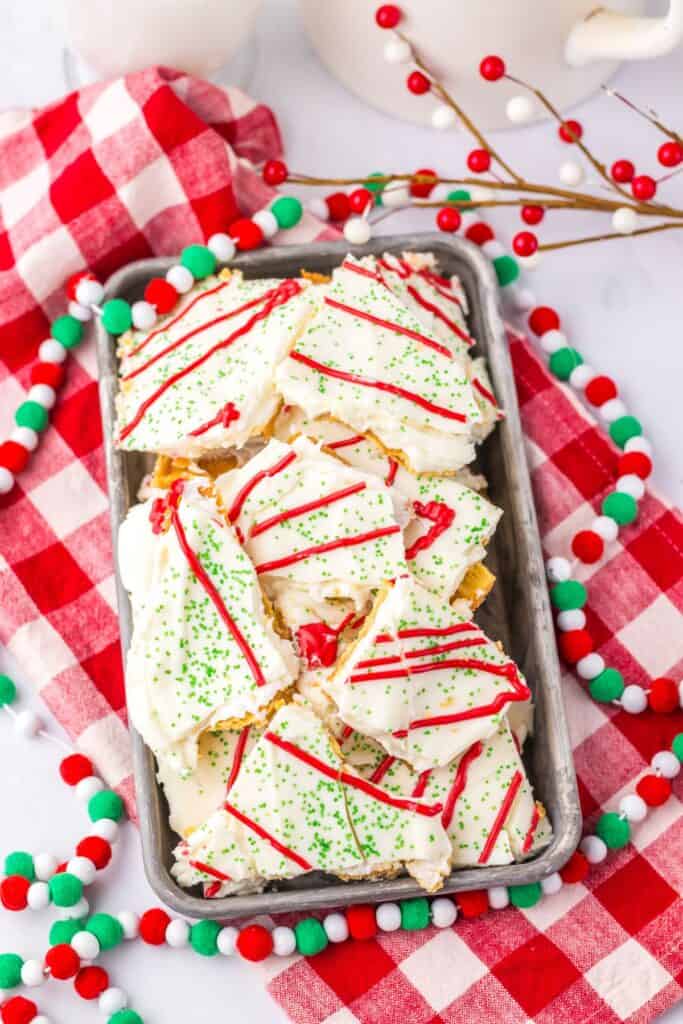 Tray of holiday-themed Christmas tree cake crack on a checkered cloth.