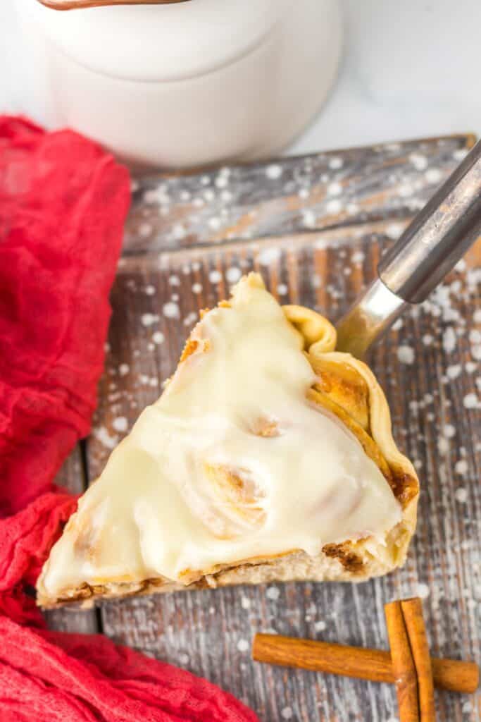 Close-up of a cinnamon roll pie slice with creamy frosting on top.