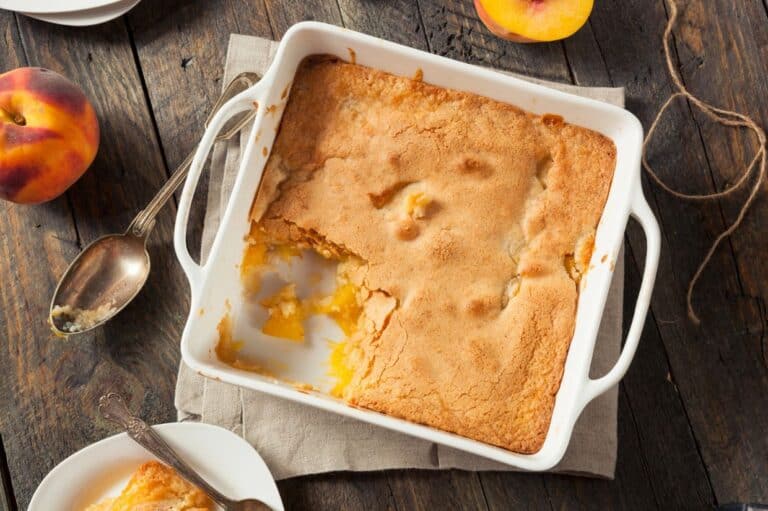 A golden-brown homemade peach cobbler served warm in a baking dish.