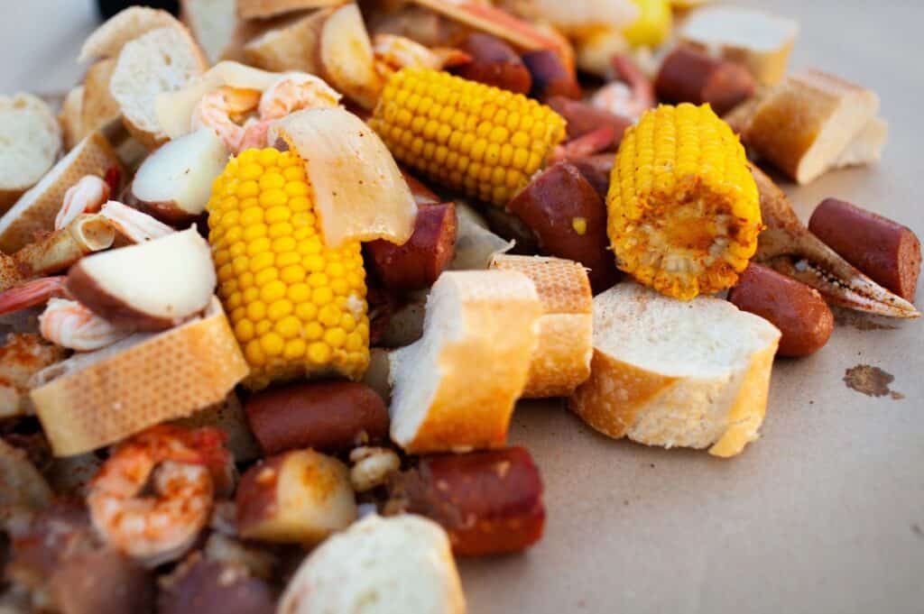 Freshly cooked Southern boil with shrimp, corn, sausage, potato, onion, and bread.