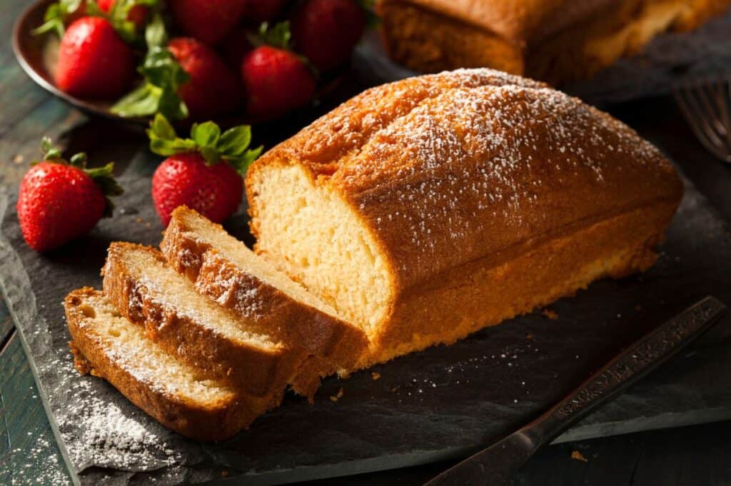 A slice of homemade pound cake with fresh strawberries served on a plate.