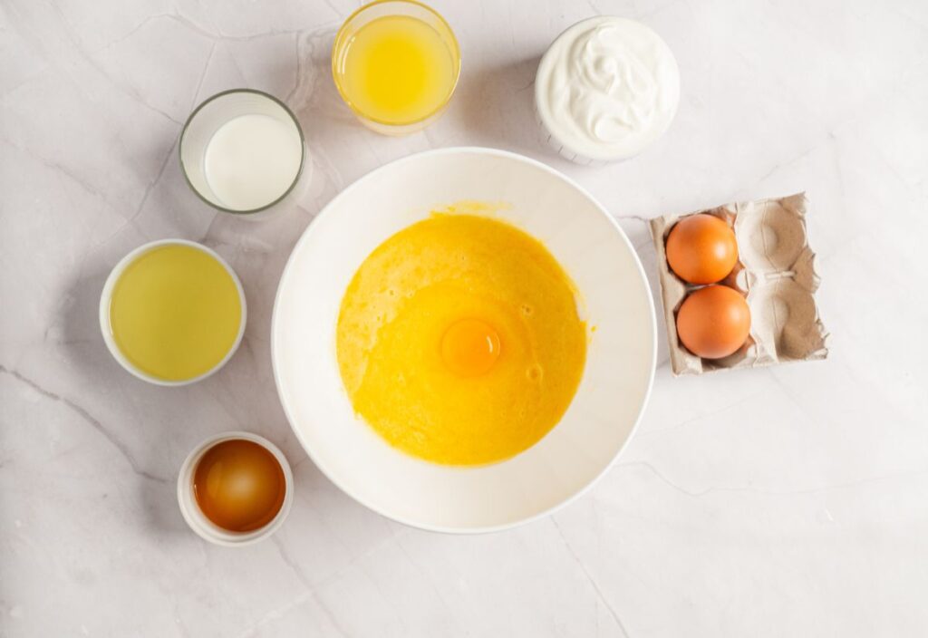 Combined zest-sugar mixture with eggs being incorporated one at a time.