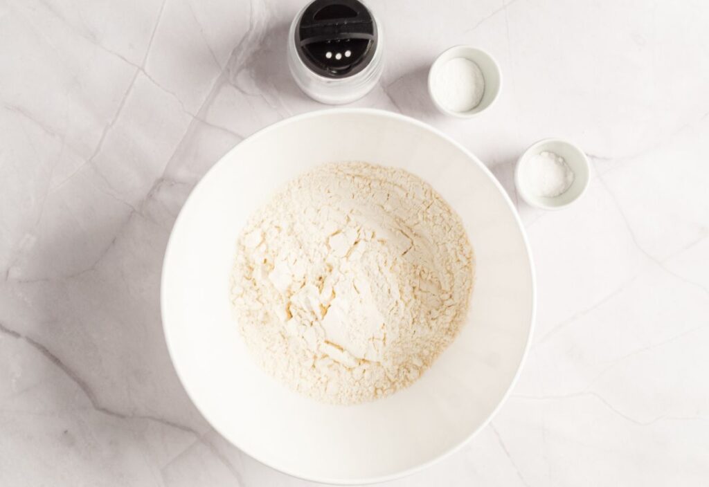 Combining flour, salt, baking powder, and baking soda in a bowl.