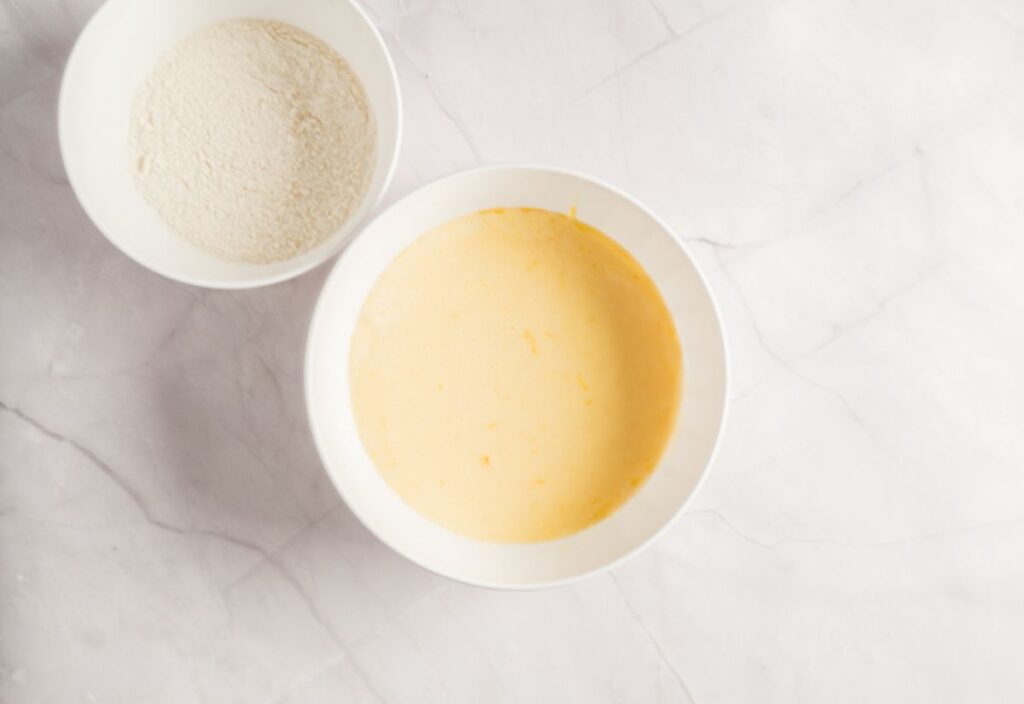 A bowl of egged lime zest mixture and another bowl of combined dry ingredients on the side.