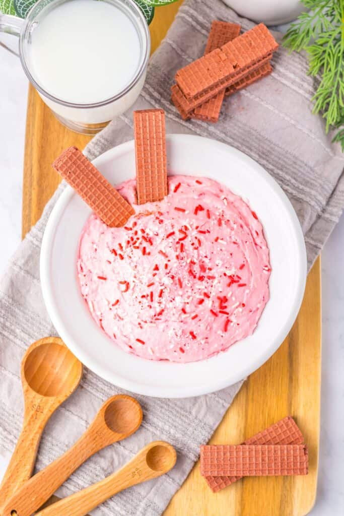 White bowl of pink peppermint fluff served with crispy wafer dippers.