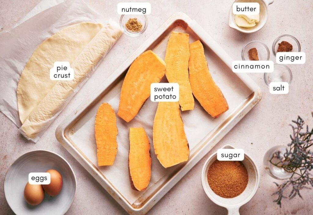 Ingredients for making sweet potato pie, including sweet potatoes, pie crust, eggs, butter, sugar, cinnamon, nutmeg, salt, and ginger, all laid out on a countertop.