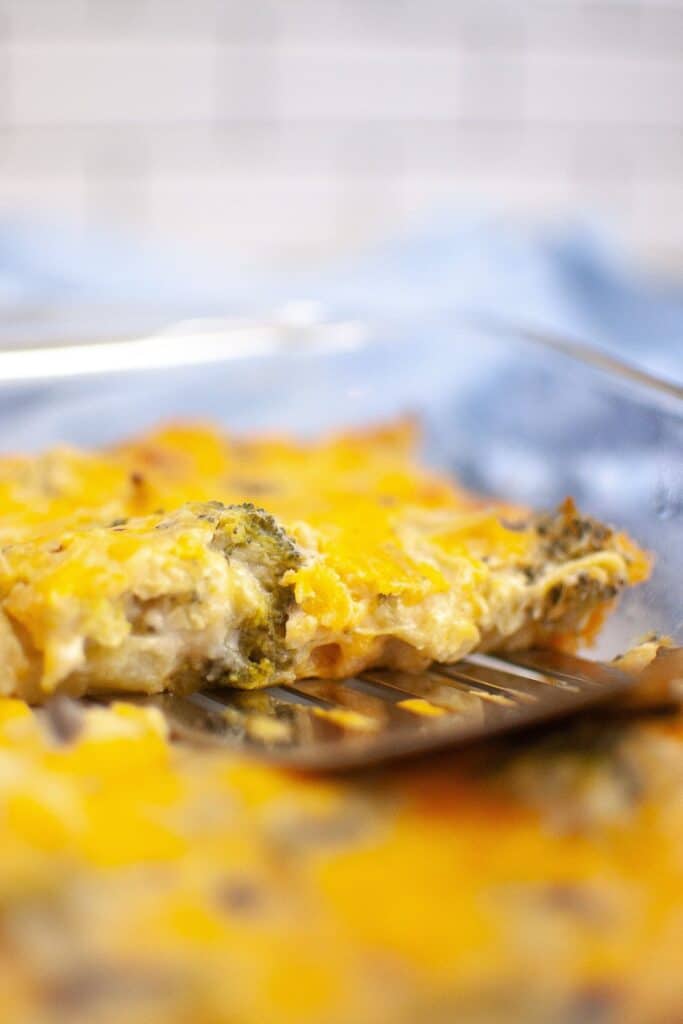 A close-up of a golden-brown broccoli cheese casserole in a glass dish, with melted cheese and broccoli visible.