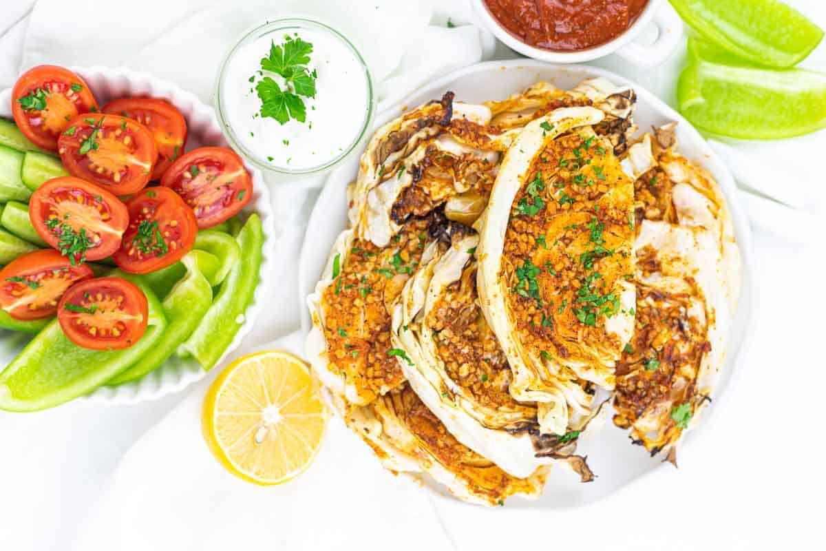 A plate of grilled cabbage wedges topped with herbs.