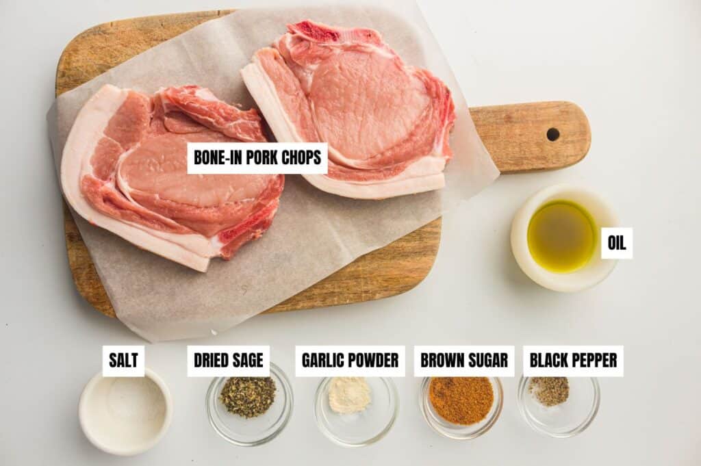 Ingredients for making air fryer pork chops are arranged on a white surface.