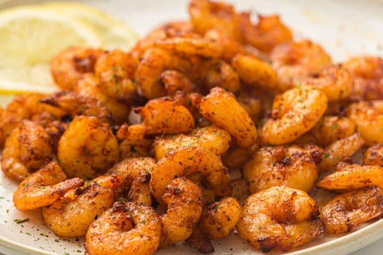 Seasoned and crispy air-fried shrimp served on a plate, garnished with fresh herbs and accompanied by lemon slices.