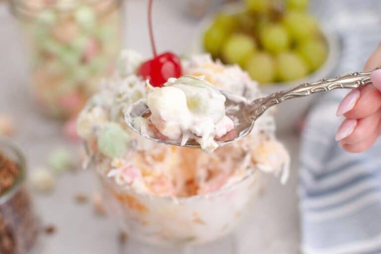 A spoonful of Ambrosia salad is held above a bowl.