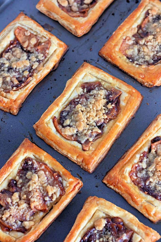 A baking tray filled with golden-brown rectangular apple crumb danishes.