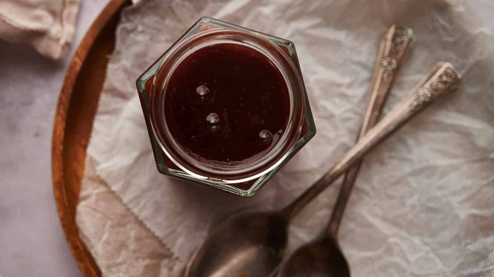 Homemade BBQ sauce in a jar with two spoons by the side.