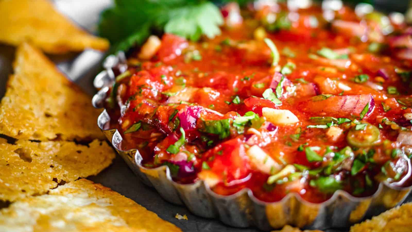 Salsa in a container with chips around.