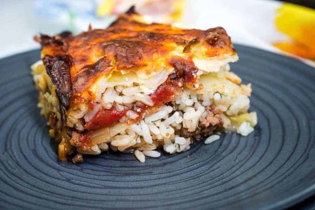 A slice of layered cabbage roll casserole served on a dark plate.