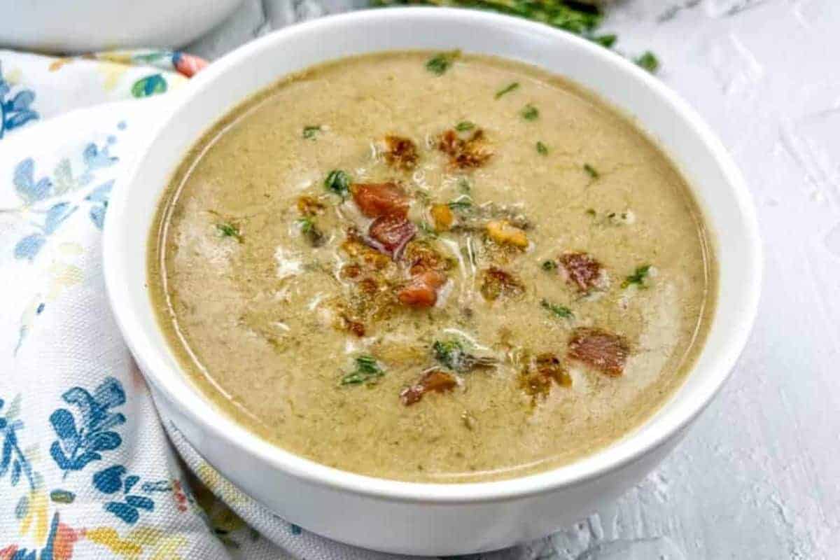 A bowl of caramelized onion & mushroom soup garnished with crispy bits and herbs on top.