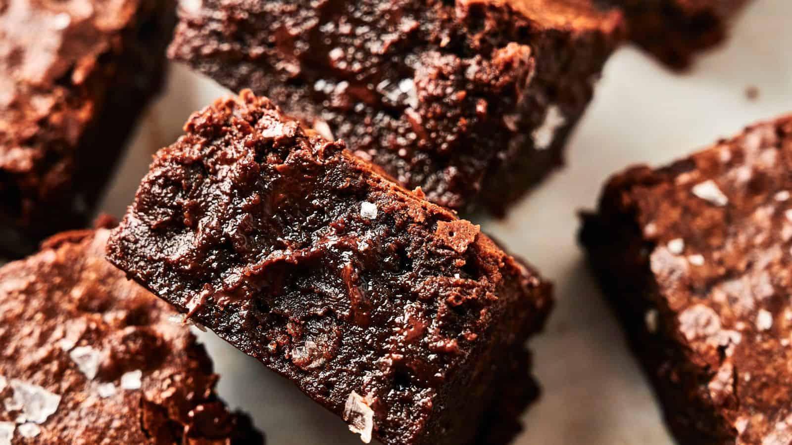 Close-up image of several chocolate brownies featuring a slightly crumbly texture and a sprinkling of coarse salt on top.