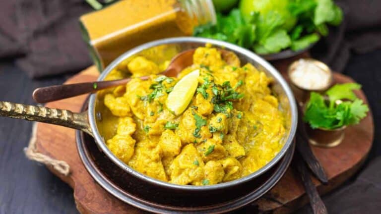 A bowl of chicken curry with a spoon.