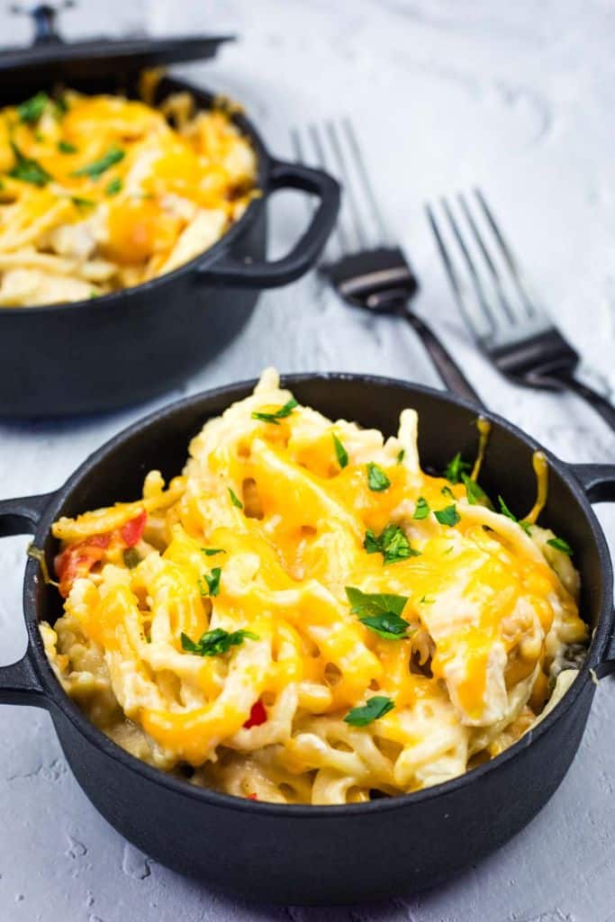 A close-up image of creamy chicken spaghetti served in small black cast-iron bowls.