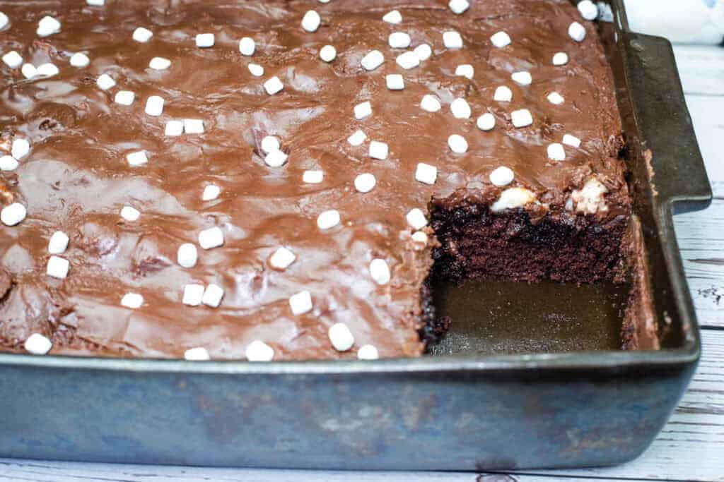 A pan of Coca-Cola cake with mini marshmallows on top, missing one square piece.